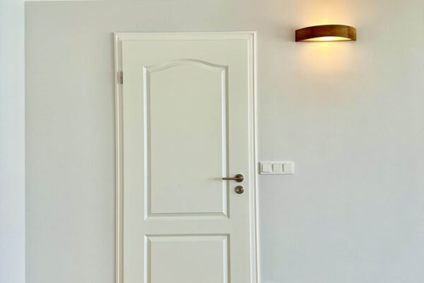 Tür in der Wohnung nach der Sanierung weiß neben der Lampe mit 3 Lichschalter und einer Steckdose